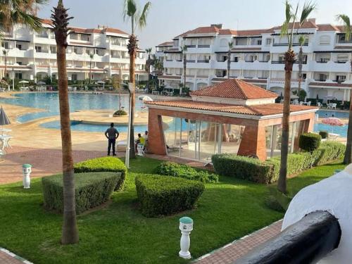a man standing next to a swimming pool in a resort at Garden Beach 2 sidi rahal in Sidi Rahal