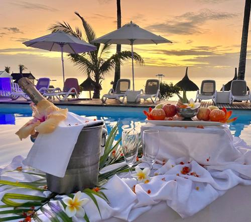 Coral Azur Beach Resort Mont Choisy في مونت تشويسي: طاولة مع طعام ومشروبات على طاولة بجانب مسبح