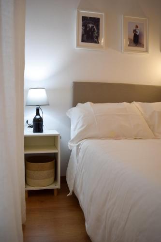 a bedroom with a white bed and a nightstand with a lamp at B&b A casa di Lò CIN F3325 in Baunei
