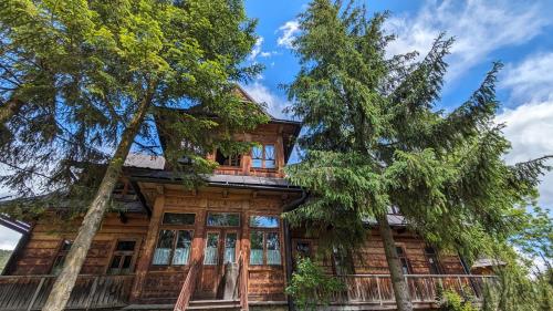 una casa de madera con árboles delante de ella en Willa Orla, en Zakopane