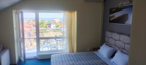 a bedroom with a bed and a window with a balcony at Hotel Neptun - Lozenets in Lozenets