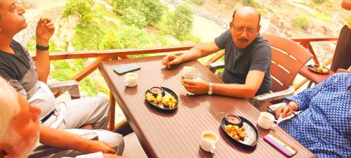 a group of people sitting at a table eating food at Hotel Prakriti Darshan in Bhatwāri