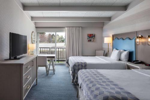 a hotel room with two beds and a flat screen tv at Howard Johnson by Wyndham Middletown Newport Area in Middletown