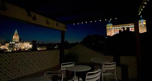 een tafel en stoelen op een balkon in de nacht bij Casón De Los López Apartments in Toledo