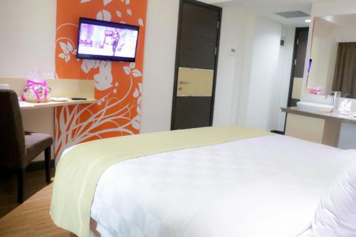 a bedroom with a bed and a tv on a wall at Dalton Hotel Makassar in Makassar