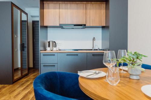 a kitchen and dining room with a wooden table and blue chairs at Apart Hotel NAVI in Batumi