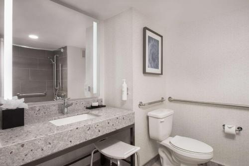 a white bathroom with a toilet and a sink at Embassy Suites by Hilton Minneapolis Airport in Bloomington
