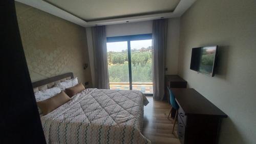ein Schlafzimmer mit Bett, Schreibtisch und Fenster in der Unterkunft H Amelkis in Marrakesch