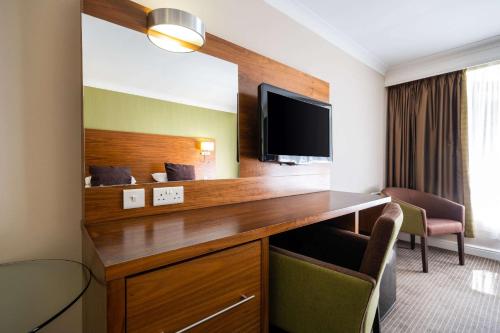 a hotel room with a desk with a flat screen tv at Holiday Inn Newcastle South by IHG in Boldon