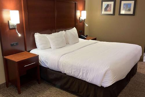 una habitación de hotel con una cama grande con sábanas blancas en Comfort Inn Indianapolis South I-65 en Indianápolis
