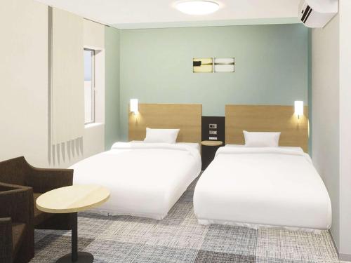 dos camas sentadas una al lado de la otra en una habitación en Comfort Hotel Kure, en Kure
