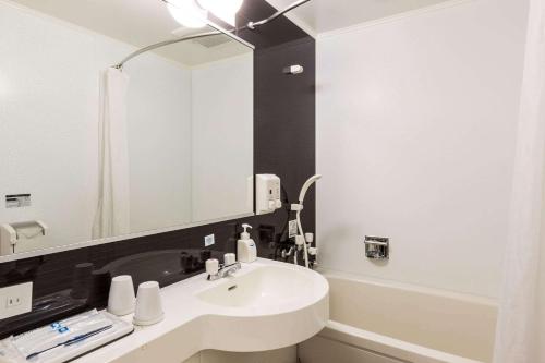 Comfort Hotel Obihiro في أوبيهيرو: حمام مع حوض ومرآة