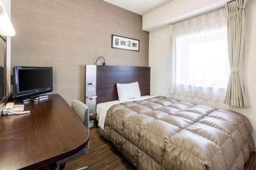 北九州市にあるコンフォートホテル黒崎のベッドとデスクが備わるホテルルームです。