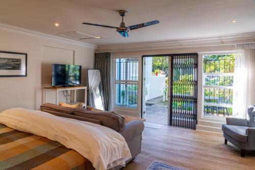 1 dormitorio con 1 cama y puerta corredera de cristal en Hedge House Guest House en Ciudad del Cabo