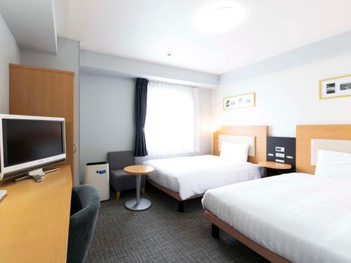 a hotel room with two beds and a flat screen tv at Comfort Hotel Hamamatsu in Hamamatsu