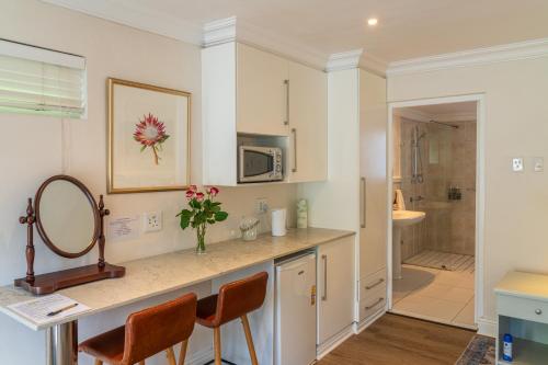 uma cozinha com um balcão com cadeiras e um lavatório em Hedge House Guest House na Cidade do Cabo