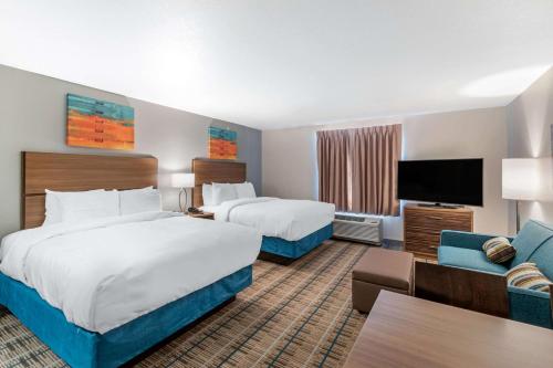 デンバーにあるMainStay Suites Denver International Airportのベッド2台、薄型テレビが備わるホテルルームです。