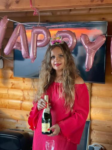 a woman in a pink dress holding a bottle of wine at Villa Melissa in Vyšné Nemecké