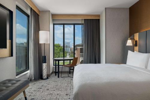 a hotel room with a bed and a desk and window at Tempo By Hilton Louisville Downtown Nulu in Louisville