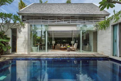 a house with a swimming pool in front of a house at Kawung Villa in Canggu