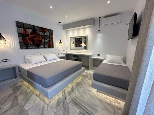 a bedroom with two beds and a desk and a television at Aphrodite Hotel & Apartments in Ios Chora