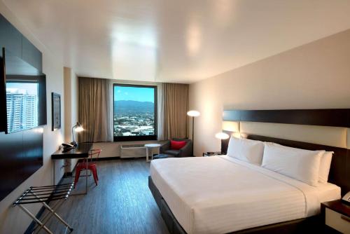 サンホセにあるパーク イン バイ サンホセ ラディソンのベッドと大きな窓が備わるホテルルームです。