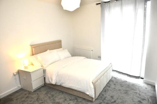a white bedroom with a white bed and a window at Sleeps 4 - Private Balcony - Wheelchair Accessible in London