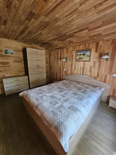 a bedroom with a large bed in a wooden room at Nameliai Šventojoje 2 in Palanga