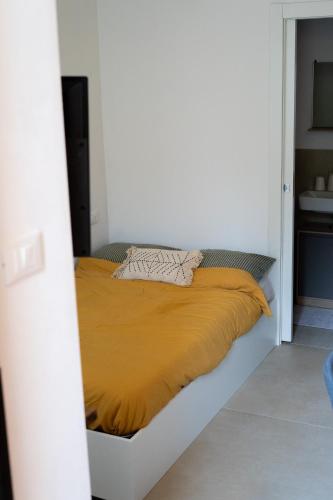 a bed in a white room with a yellow blanket at the lake room in Nago-Torbole