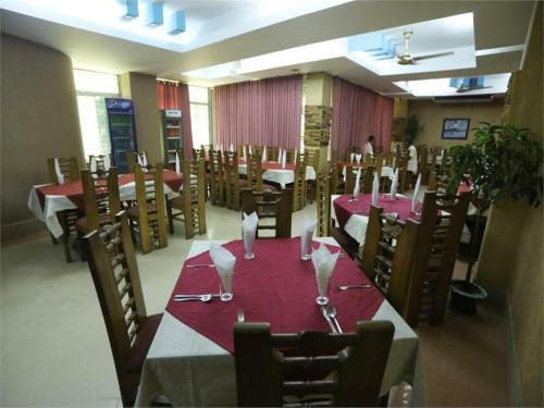 a dining room with tables and chairs with wine glasses at Britannia Hotel in Sylhet