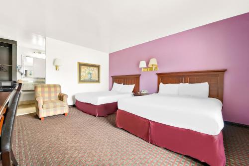 a hotel room with two beds and a chair at Capitol Inn and Suites in Montgomery