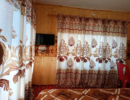 a bedroom with a bed and a curtain and a tv at Green Street in Pahalgām