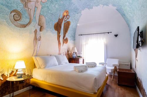 a bedroom with a white bed with a painting on the wall at Villa Vittoria Hotel in Alcamo