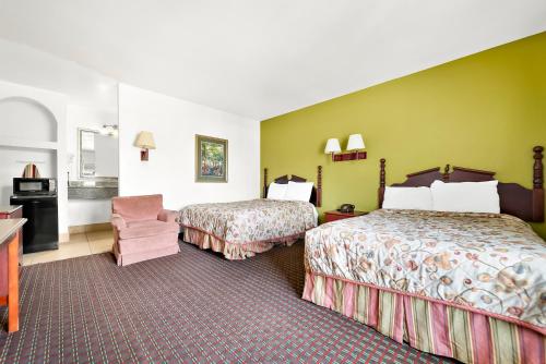 a hotel room with two beds and a chair at Capitol Inn and Suites in Montgomery