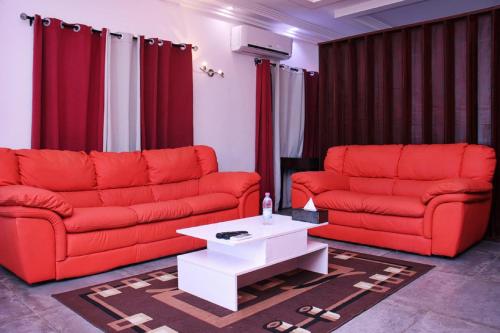 a living room with two red couches and a coffee table at Hôtel Guest House Quatre Saisons in Cadjèhoun