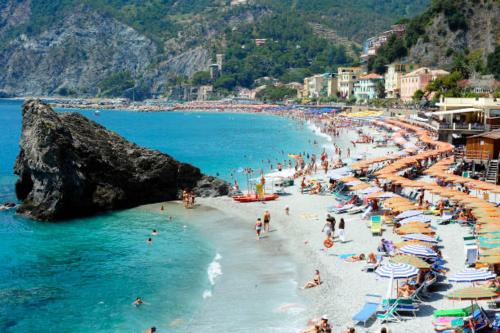 a group of people on a beach with umbrellas at La Primula Vicinanza 5 Terre in Riccò del Golfo di Spezia