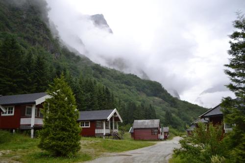 a group of houses on a dirt road next to a mountain at Gudvangen Camping in Gudvangen