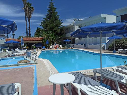 a swimming pool with chairs and tables and umbrellas at Giovanni Apartment 21 Kos in Kos Town