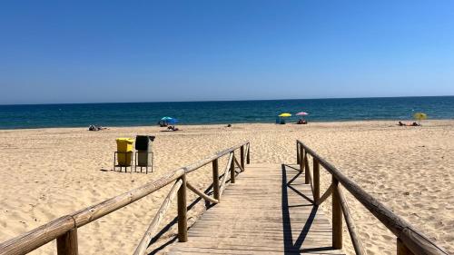 una passerella di legno che conduce a una spiaggia con ombrelloni di Casa adosada en Urbasur ISLANTILLA a Islantilla