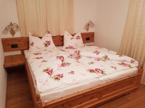 a bed with white sheets and pink flowers on it at Neuhäusel-Hof Appartments in Avigna