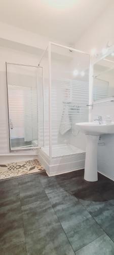 une salle de bain blanche avec un lavabo et un miroir dans l'établissement Studio Escale Plage avec piscine, au Grau-du-Roi