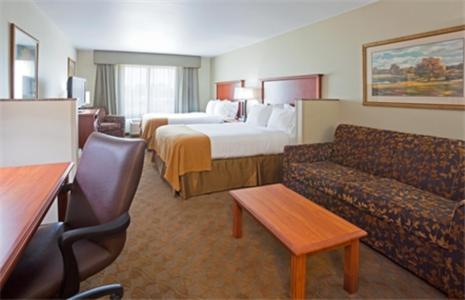 Holiday Inn Express & Suites - Mason City, an IHG Hotel في ماسون سيتي: غرفه فندقيه بسرير واريكه