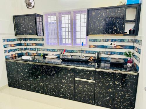 uma cozinha com armários pretos e um lavatório em Spacious 2BHK Near Airport em Cochin