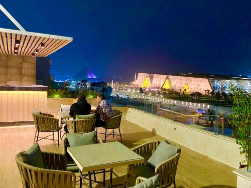 two people sitting at tables on a balcony at night at New Museum, Pyramids inn in Cairo