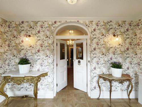 a hallway with floral wallpaper and two console tables at Glenastar Lodge in Newcastle West