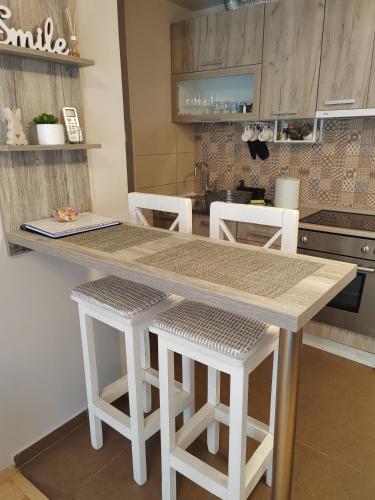 a kitchen with a table and some white stools at Apartman_Krstić_1 in Subotica