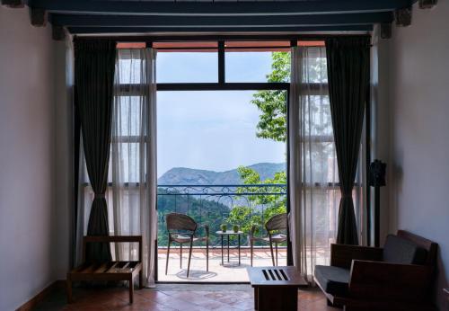 a living room with a large window with a view at Mango Hill Yercaud in Yercaud