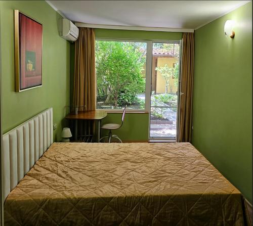 a bedroom with a bed and a window and a desk at Cozy Place - в центъра, само на 5 минути пеша от плажа in Burgas