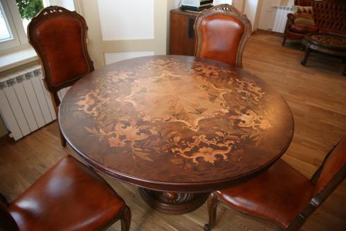 a wooden table with leather chairs around a wooden floor at Aparthotel Stora Antis in Klaipėda
