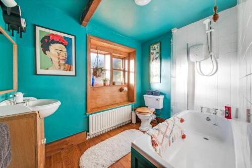 a bathroom with blue walls and a tub and a toilet at Cottage Pie - 10mins easy walk to Holmfirth in Holmfirth